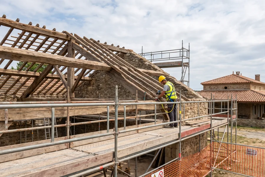 Charpentier travaillant sur une charpente bois traditionnelle dans l'Aude